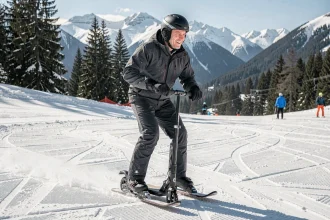 Adulte testant une patinette ski sur une piste de montagne enneigée lors d'une session en station